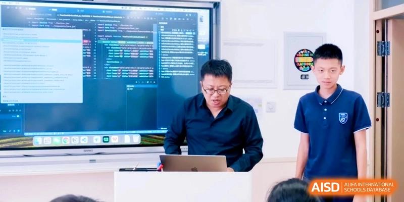 A male instructor works on a laptop in front of a digital display showing lines of programming code at Shanghai Qingpu World Foreign Language High School.