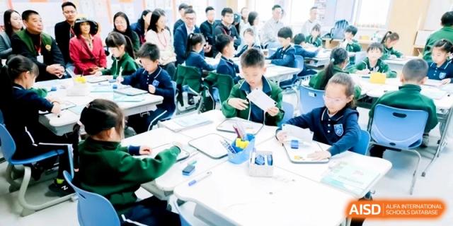 Students work in small groups at white tables, collaborating on a hands-on project at Shanghai Qingpu World Foreign Language High School.