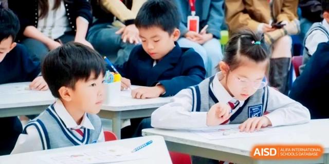 Focused young students write diligently at their desks during a classroom activity at Shanghai Qingpu World Foreign Language High School.