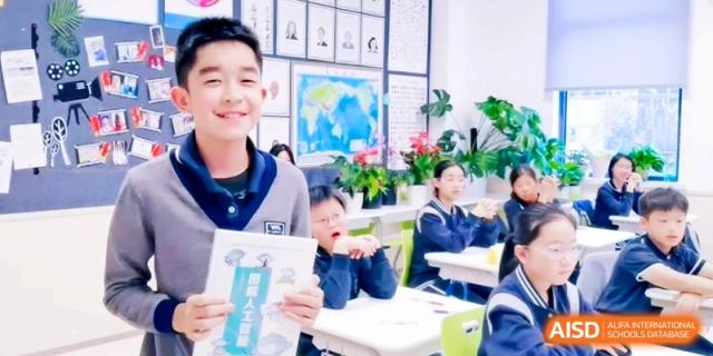 A smiling student holds up a workbook during a lesson in a bright classroom at Shanghai Qingpu World Foreign Language High School.