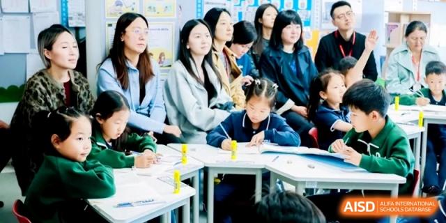 A group of students and observers listen intently during a collaborative class session at Shanghai Qingpu World Foreign Language High School.