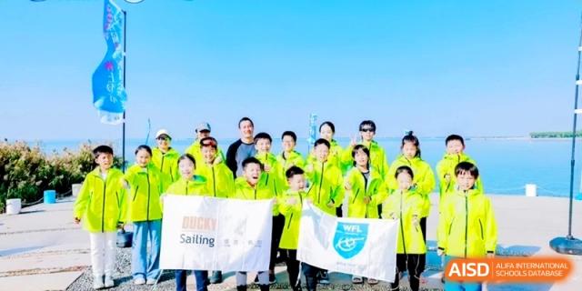 Large group of students in bright green jackets holding flags for a sailing event at Shanghai Qingpu World Foreign Language High School.