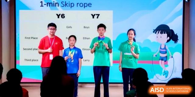 Three students standing on stage wearing medals during a Year 6 and Year 7 ceremony at Shanghai Qingpu World Foreign Language High School.