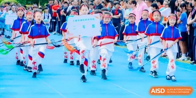 Young students in traditional red and white athletic uniforms marching during a sports day at Shanghai Qingpu World Foreign Language High School.
