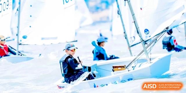 A student skillfully navigating a small sailboat on the water during a training session at Shanghai Qingpu World Foreign Language High School.