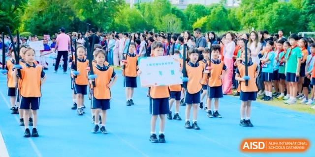 Students in orange sports vests lined up on an outdoor blue track for an event at Shanghai Qingpu World Foreign Language High School.