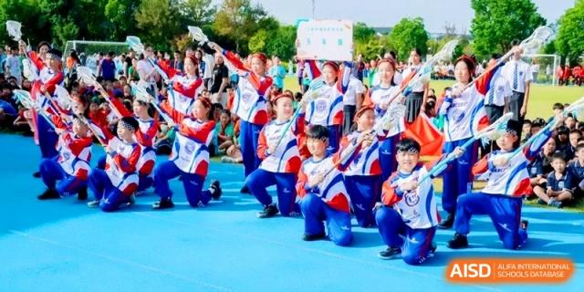 A cheerleading or dance squad performing a routine on an outdoor blue mat at Shanghai Qingpu World Foreign Language High School.