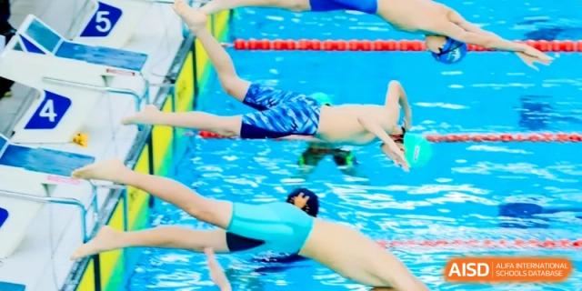 Swimmers captured mid-dive into a pool during a competitive swimming meet at Shanghai Qingpu World Foreign Language High School.