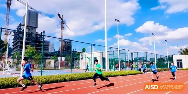 A determined student in a green shirt sprints quickly down the red running track during a competitive track and field event at Shanghai Qingpu World Foreign Language High School.
