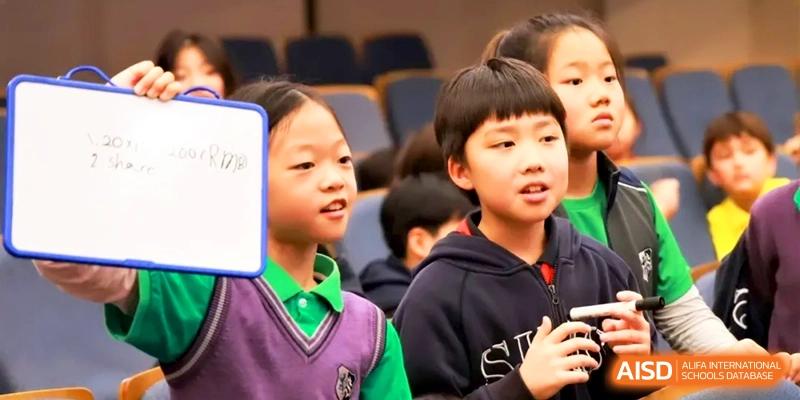 Two students in purple uniforms participate in an engaging classroom presentation or discussion at Shanghai United International School, Hongqiao Campus.