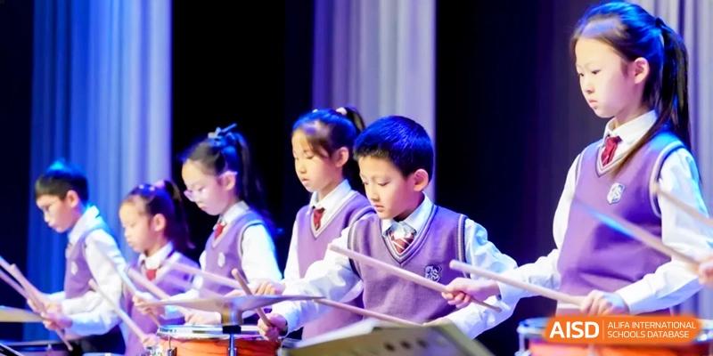 A group of students in purple uniforms play xylophones together during a music performance at Shanghai United International School, Hongqiao Campus.