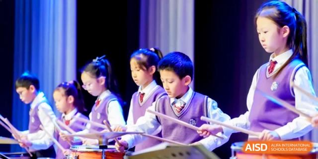 A group of students in purple uniforms play xylophones together during a music performance at Shanghai United International School, Hongqiao Campus.