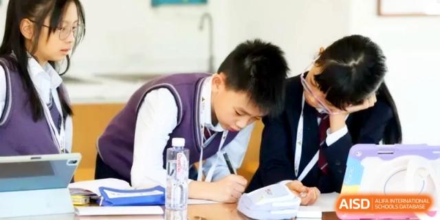 A student focuses intently on writing or drawing in a notebook during a class lesson. | Shanghai United International School, Hongqiao Campus