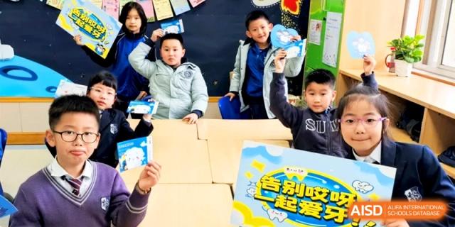 Excited students hold up their completed project boards during a classroom presentation. | Shanghai United International School, Hongqiao Campus