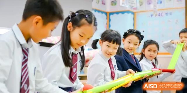 Students participate in a physical education activity using long yellow foam batons. | Shanghai United International School, Hongqiao Campus