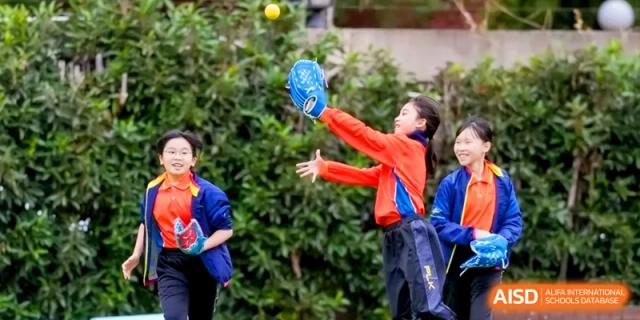 An enthusiastic student athlete jumps to catch a yellow ball during an outdoor sports game on the school's athletic field at Shanghai United International School, Hongqiao Campus