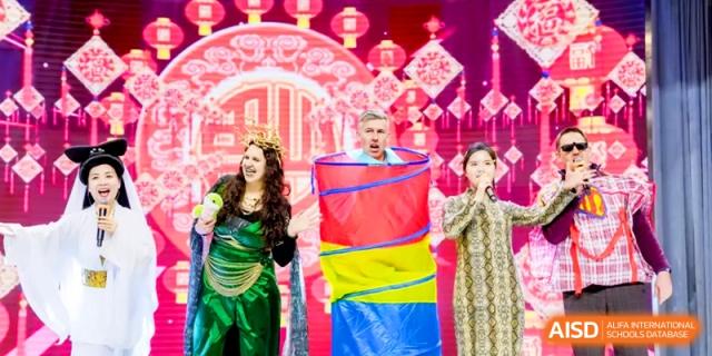 Three performers engage in a colorful stage production with vibrant red backdrops at Shanghai United International School, Hongqiao Campus