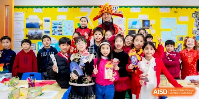 A large group of students and a teacher in festive red clothing pose together for a photo at Shanghai United International School, Hongqiao Campus