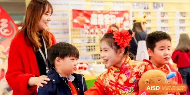 Two students in traditional red outfits share a smile during a cultural event celebration at Shanghai United International School, Hongqiao Campus