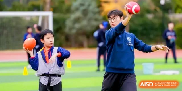 A student athlete prepares to throw a ball during a physical education class on the green field at Shanghai United International School, Hongqiao Campus