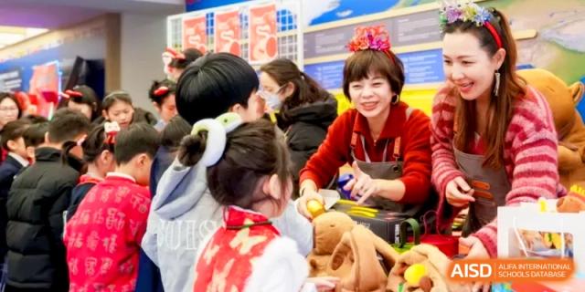 A teacher and students engage in a hands-on creative craft activity during a vibrant cultural event at Shanghai United International School, Hongqiao Campus