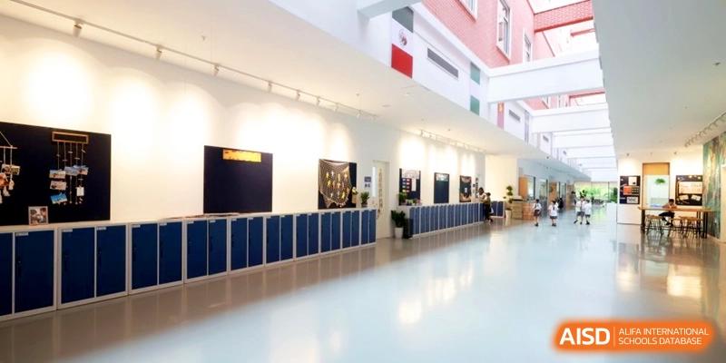 Bright school hallway with blue lockers and bulletin boards on white walls at Shanghai United International School, Pudong