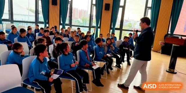 Group of primary students sitting in a bright room with large windows at Shanghai United International School, Pudong