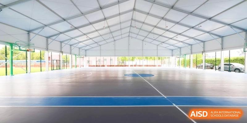 Large indoor multi-purpose sports court with blue and grey flooring at Shanghai United International School, Pudong