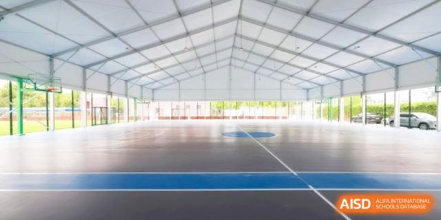 Large indoor multi-purpose sports court with blue and grey flooring at Shanghai United International School, Pudong