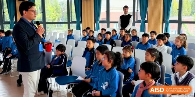 Students gathered in a modern assembly hall with a teacher standing nearby at Shanghai United International School, Pudong
