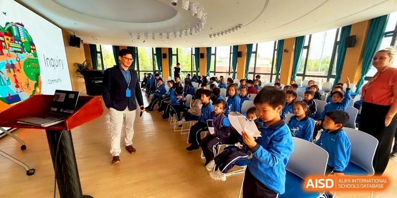 Students in blue uniforms sitting in rows during a presentation in the auditorium at Shanghai United International School, Pudong