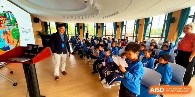 Students in blue uniforms sitting in rows during a presentation in the auditorium at Shanghai United International School, Pudong