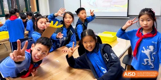 Happy students posing and making peace signs in a classroom setting at Shanghai United International School, Pudong