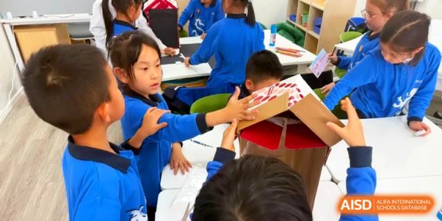 Students working together on a creative craft project at a classroom table at Shanghai United International School, Pudong