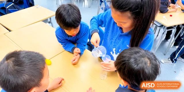 Students carefully pour liquids into containers during a collaborative science activity in a bright room at Shanghai United International School, Pudong