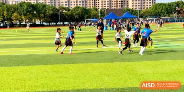 Young children participate in a flag football match on a sunny day on the school's outdoor sports field at Shanghai United International School, Pudong