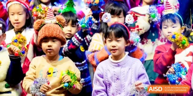 Young children wearing colorful winter hats and holiday accessories participate in a school celebration at Shanghai United International School, Pudong