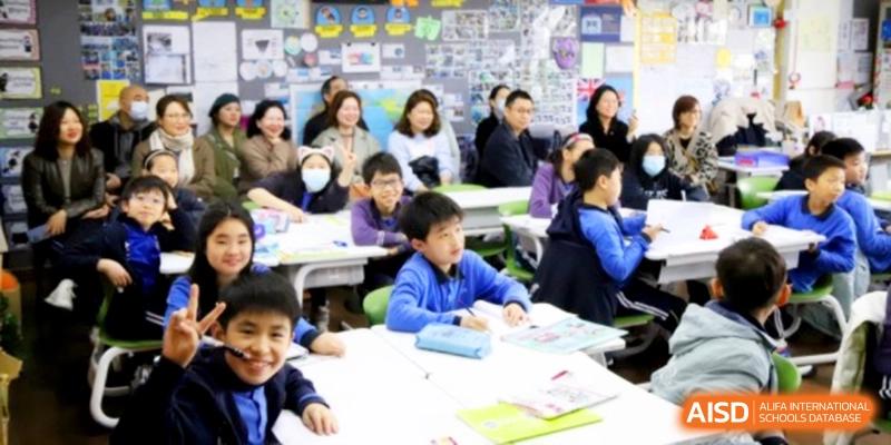 A diverse group of elementary students sitting at their desks in a bright classroom during a lesson at Shanghai United International School, Shangyin Campus.
