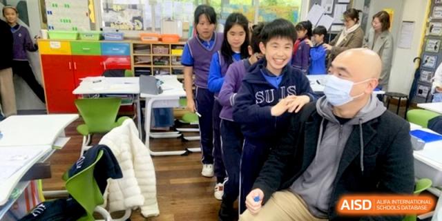 Students in blue uniforms stand in a line during a classroom activity at Shanghai United International School, Shangyin Campus.