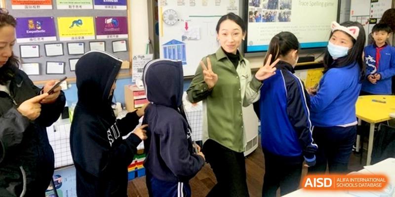 A teacher in a green shirt interacts with a student in a hoodie in class at Shanghai United International School, Shangyin Campus.