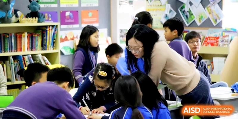 A group of young students working together on a desk project in a classroom at Shanghai United International School, Shangyin Campus.
