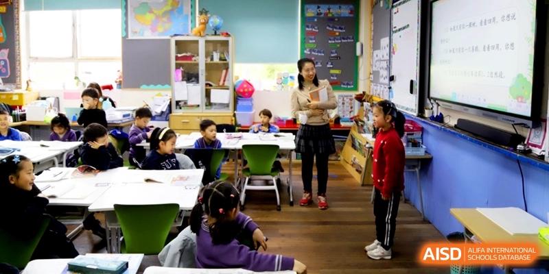 A teacher standing in a classroom while students sit at their desks at Shanghai United International School, Shangyin Campus.