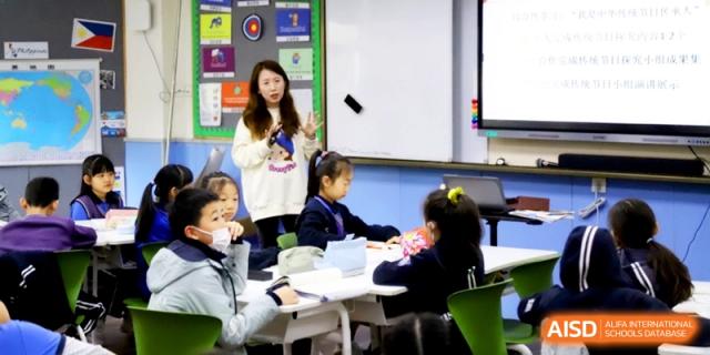 A teacher presenting a lesson to attentive students sitting at their desks in a bright classroom at Shanghai United International School, Shangyin Campus.
