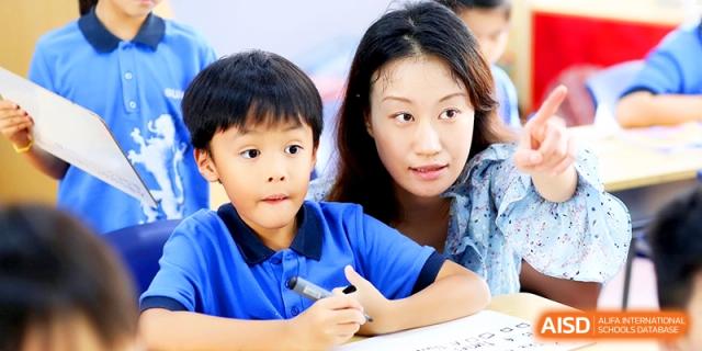 A teacher providing one-on-one guidance to a young student during a focused classroom activity at Shanghai United International School, Shangyin Campus.
