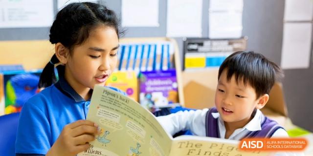 A close-up of a student engaged in reading a colorful children's book in the school library at Shanghai United International School, Shangyin Campus.