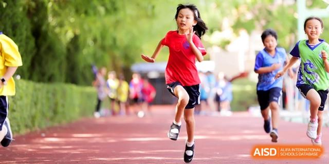 A young student in a red shirt sprinting on a track during a sports day at Shanghai United International School, Shangyin Campus.