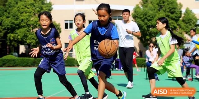 Students practicing basketball drills on an outdoor court with their coach at Shanghai United International School, Shangyin Campus.