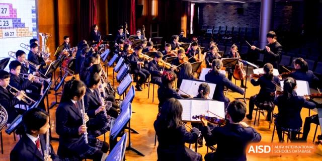 A student orchestra performing with violins and cellos during a concert at Shanghai United International School, Shangyin Campus.