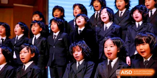 A children's choir in formal black suits singing during a school performance at Shanghai United International School, Shangyin Campus.