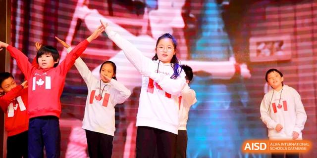 Students in white hoodies perform a synchronized dance routine on stage at Shanghai United International School, Shangyin Campus.